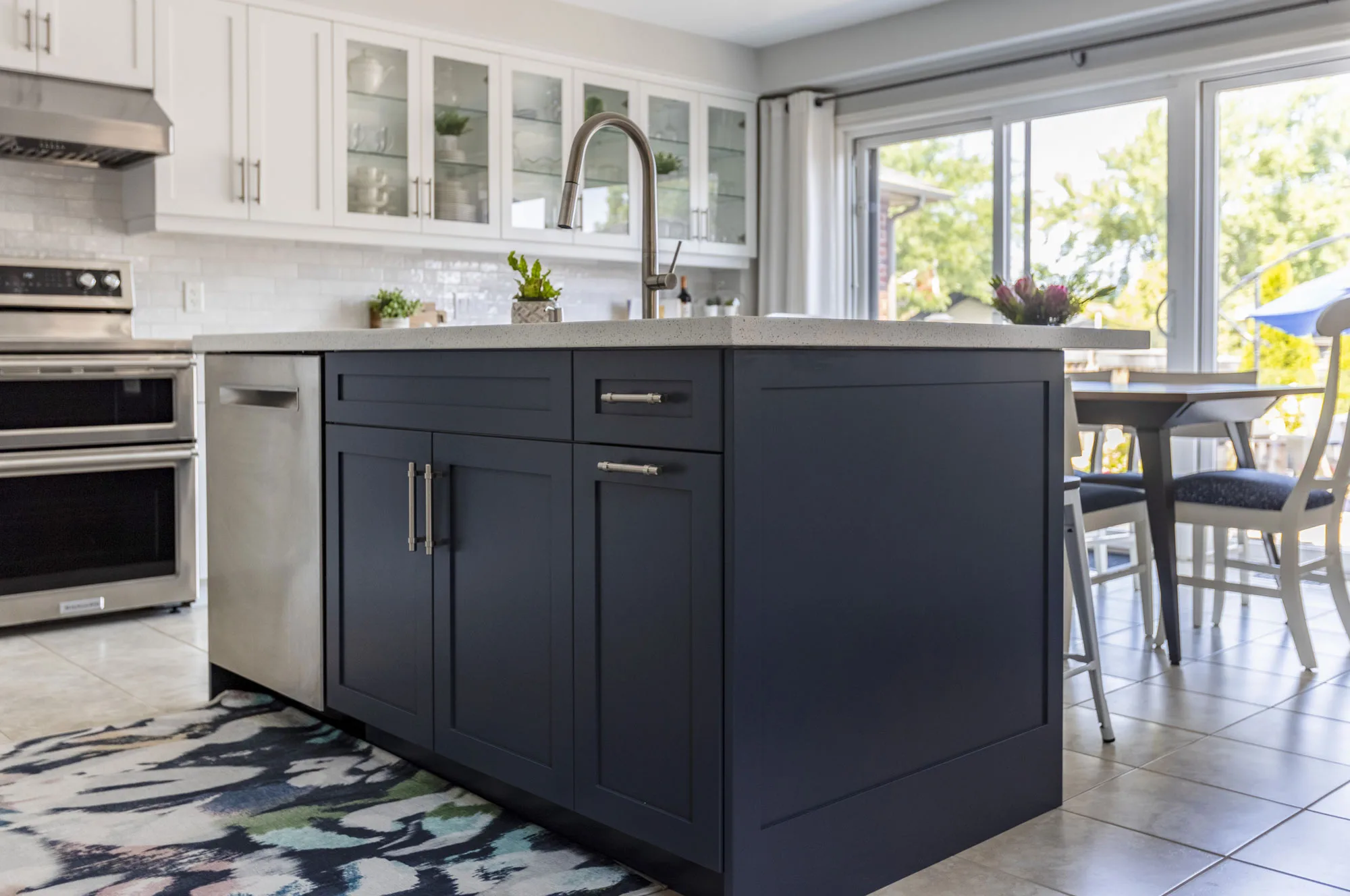 A dark blue kitchen island with silver handles and a stainless steel dishwaher