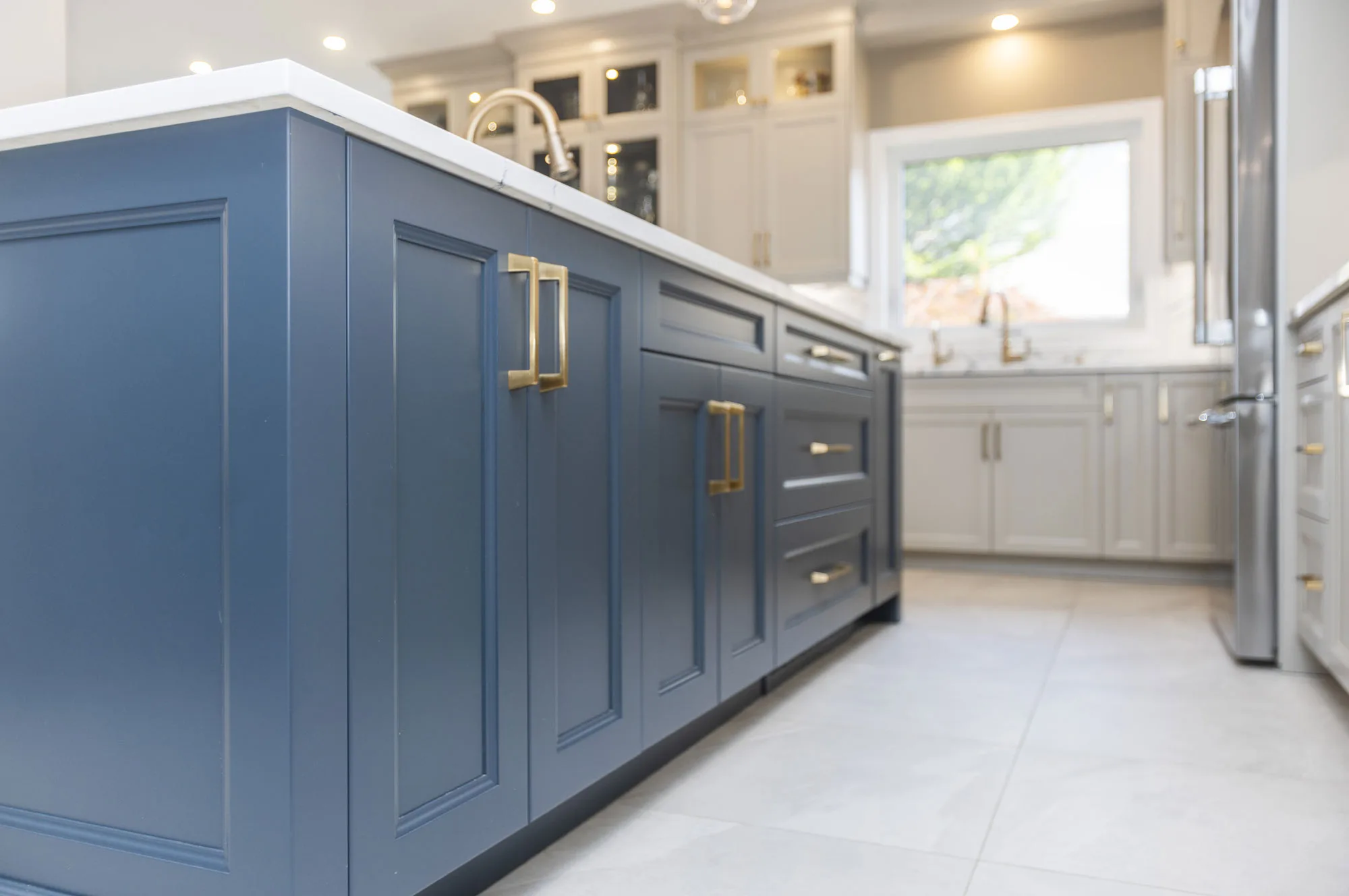 A close up of a dark blue cabinets on a kitchen island with gold handles.
