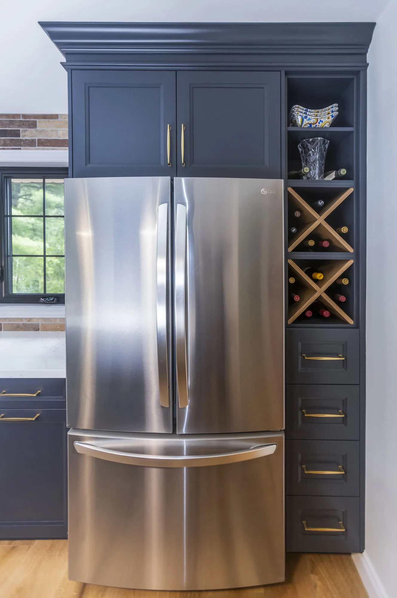 A close up of a stainless steal fridge with dark navy uppers on top and along the side.