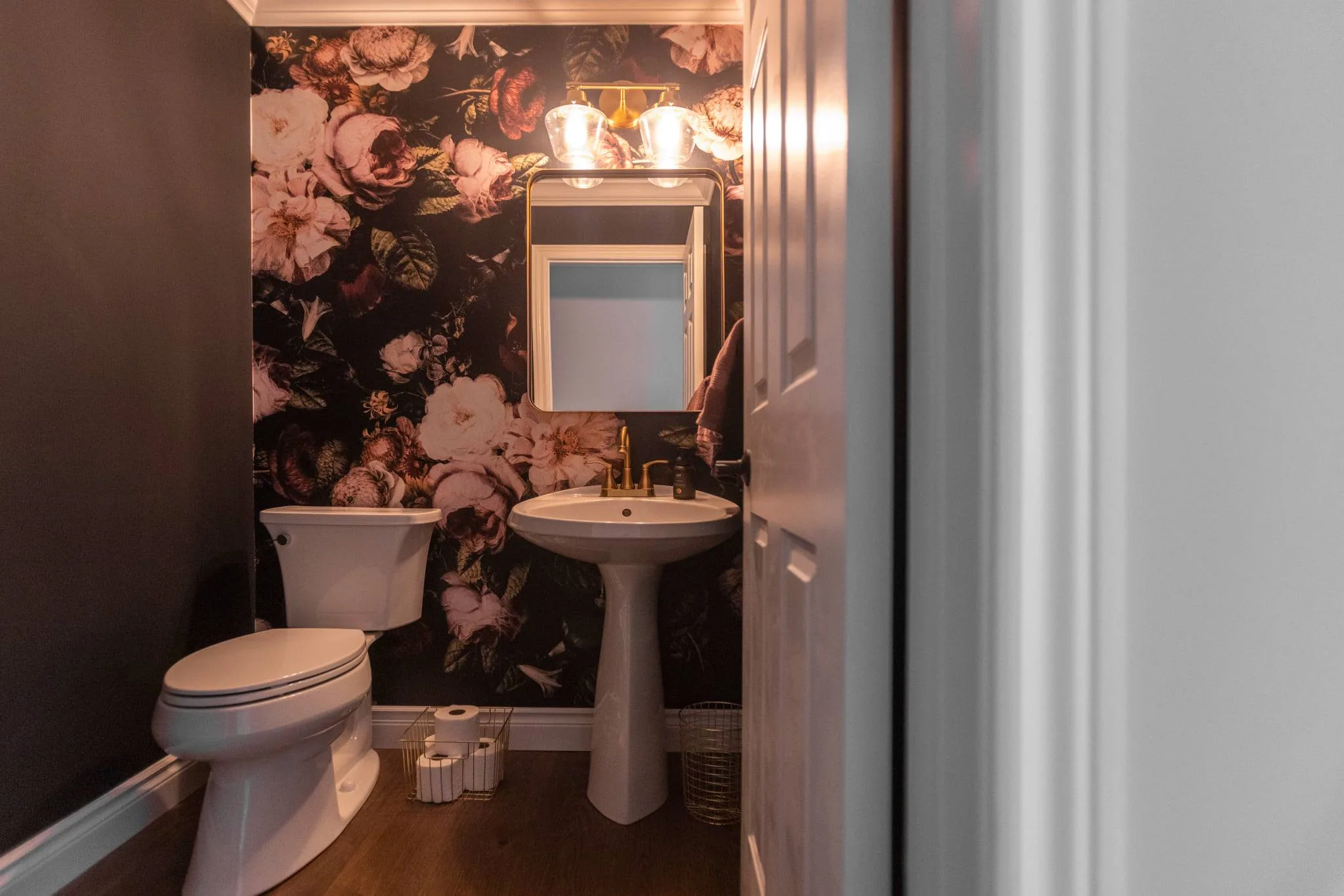 Powder room with beautiful floral wall paper with pedistal sink and mirror