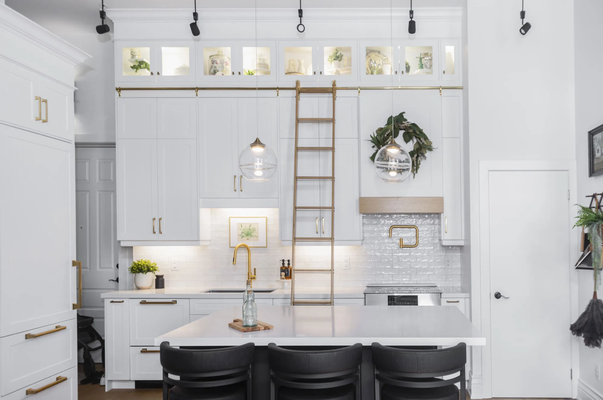 a beautiful white kitchen with accents in gold along with a gold ladder