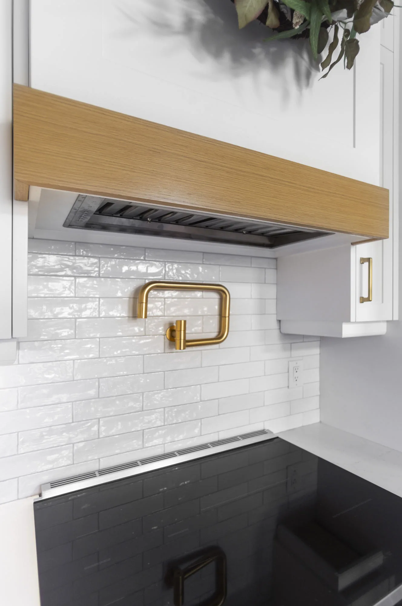 Close up a stove top with white back splash and gold water spout