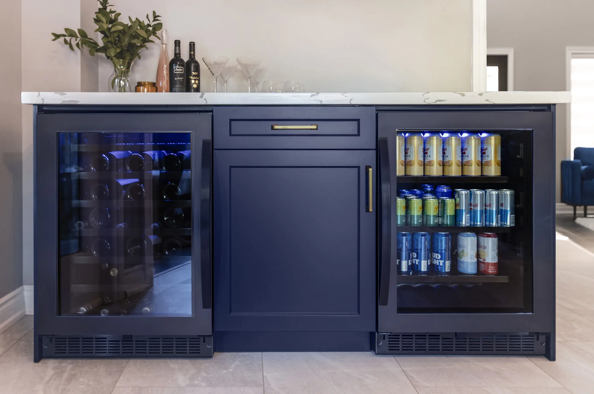Close up of a kitchen wine and drink island with dark blue cabinets and white counter top