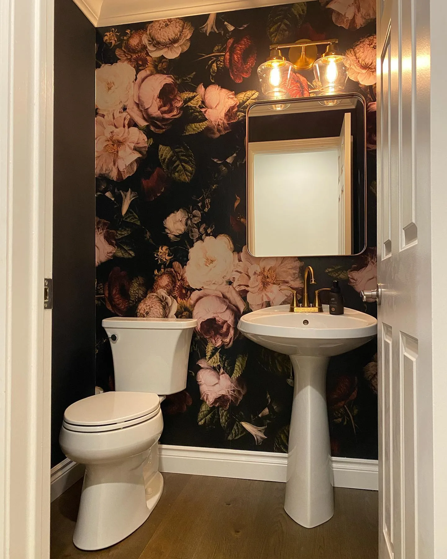 Powder room with beautiful floral wall paper with pedistal sink and mirror